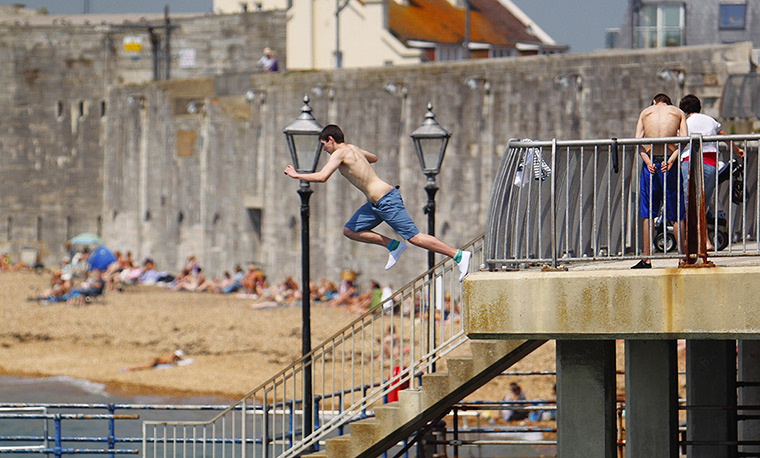 UK heatwave: A man leaps into the sea as people enjoy the sun on the beach in Portsmouth