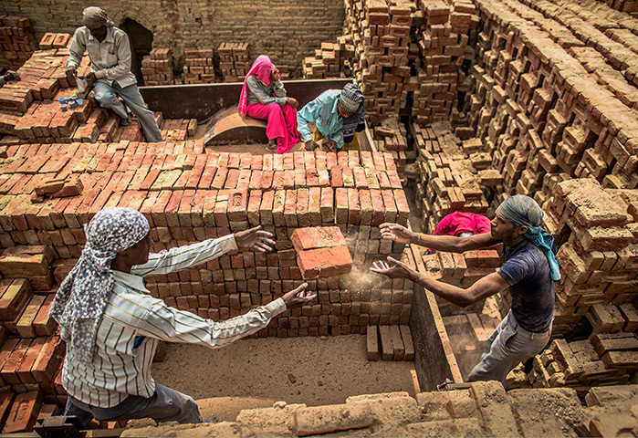 24 hours in pictures: Labourers pass baked bricks at a factory India