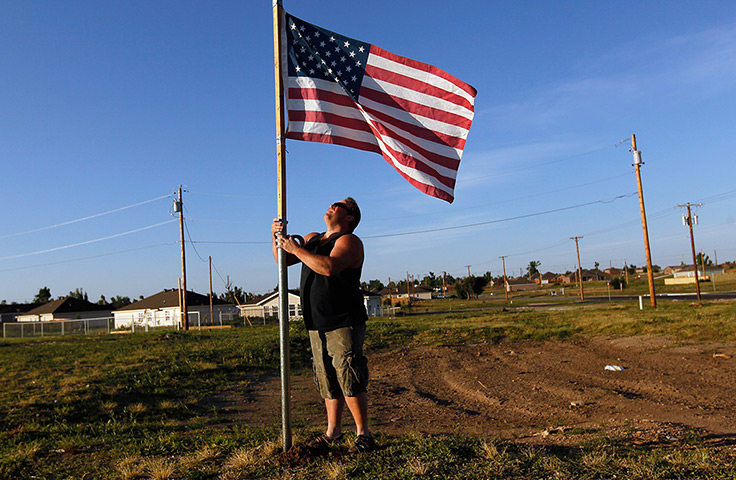 FTA: Joe Raedle: A man places an American flag next to where his house was 