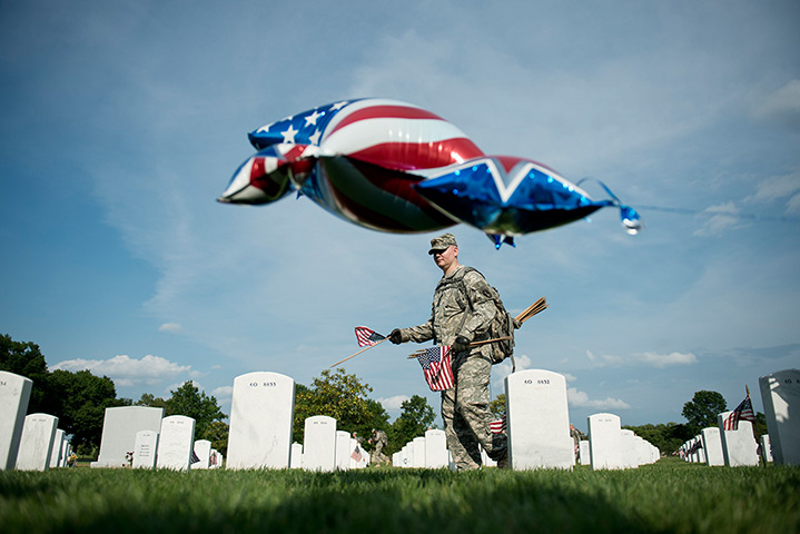 24 hours in pictures: A soldier plants a flag at a grave in at Arlington National Cemetery