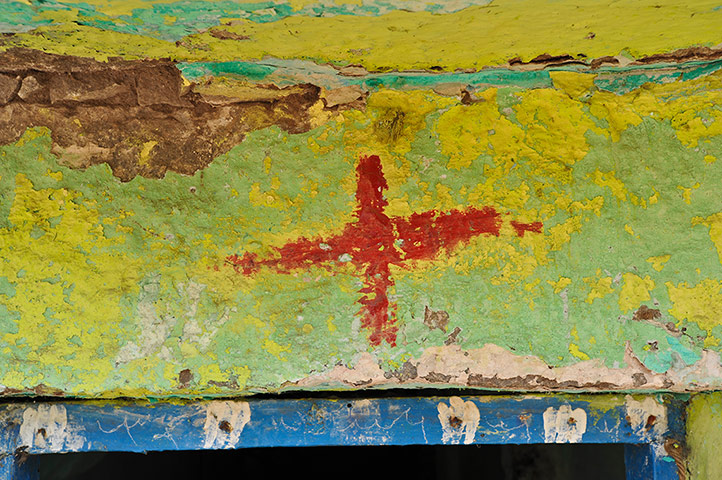 Hampi: A red cross painted on a building in the Hampi bazaar 