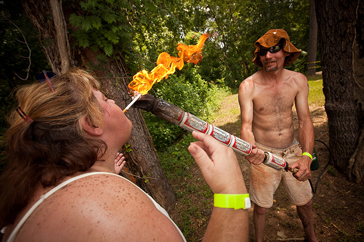 Redneck games: The carrier of the beer can torch lights a woman's cigarette 