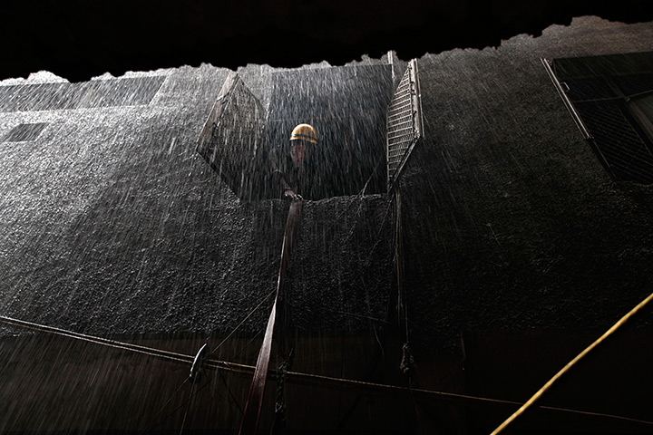 24 hours: New Delhi, India: An Indian fire fighter pulls a water hose after a fire