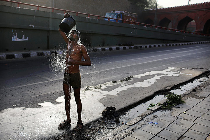 24 hours: New Delhi, India: An Indian migrant laborer washes himself as he cools off