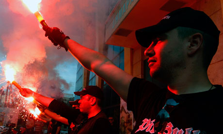 Greek extreme right Golden Dawn party hold red flares outside the town hall of Perama town