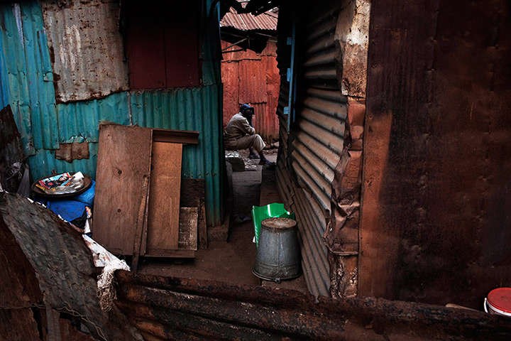 Sierra Leone Architecture: A man listens to the radio amidst a collection of homes