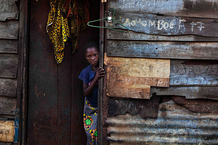 Sierra Leone Architecture: A girl looks out of the door in Murray Town