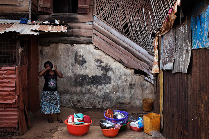 Sierra Leone Architecture: A woman combs her hair in the back courtyard in Murray Town