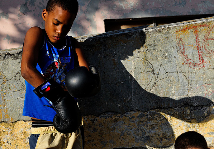 24 hours: Havana, Cuba: A boy puts his gloves on during a boxing practice