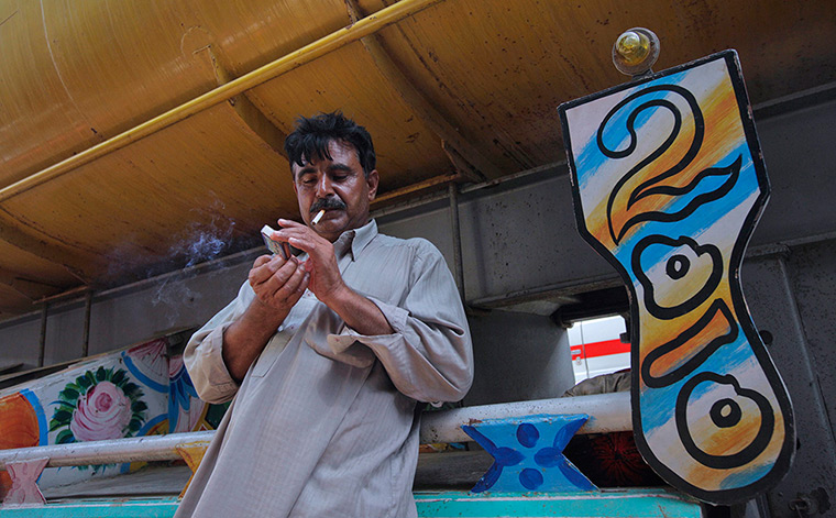 24 hours: Karachi, Pakistan: A driver lights up a cigarette by a fuel tanker