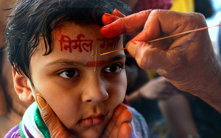 24 hours: Allahabad, India: A holy man applies paste on the forehead of a child