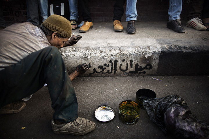 24 hours in pictures: An Egyptian man paints graffiti on a pavement during a political rally