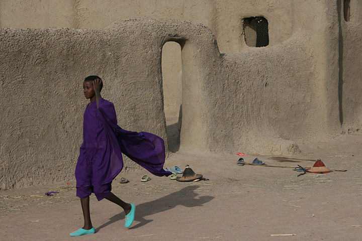 Your Pictures: Your Pictures: girl in purple walking past mud building in Mali