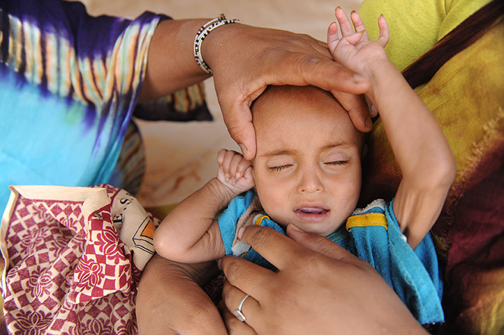 Longer View: A Malian child and his parents wait to be treated at Mbere refugee camp