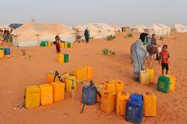 Longer View: Malian refugees stand at a water distribution point