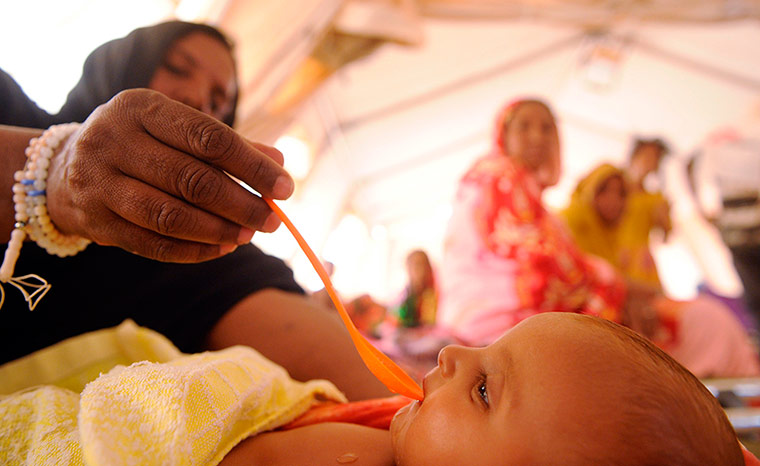 Longer View: A woman tends to a malnurished Malian refugee child at the MSF center