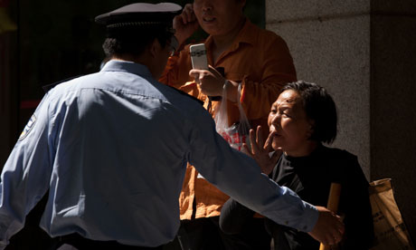 A Chinese woman is approached by police outside the hopital where Chen Guangcheng is being treated