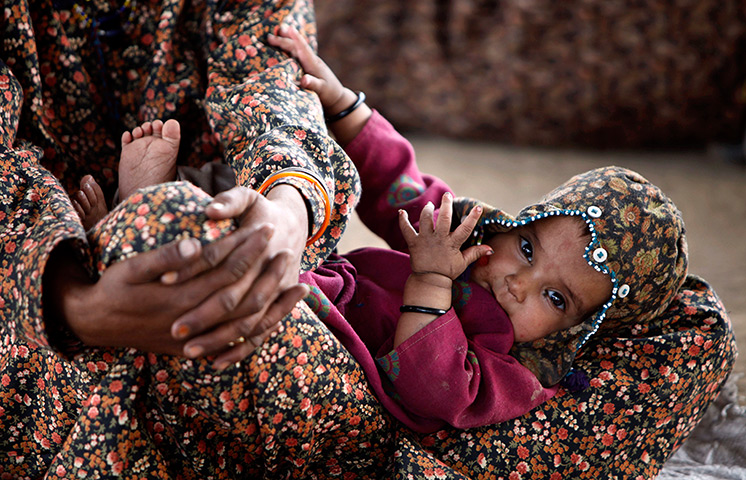 Supermoon: An Indian nomadic Gujjar child lies on the lap of her mother