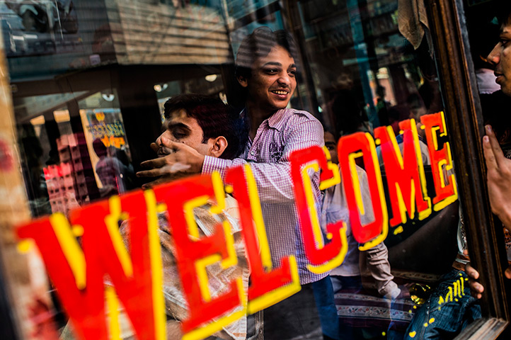 24 hours in pictures: A barber talks to a friend as he applies after shave to a customer