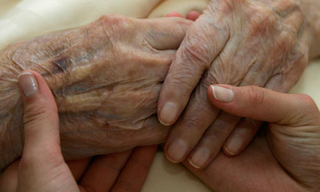 Carer holds hands of elderly woman
