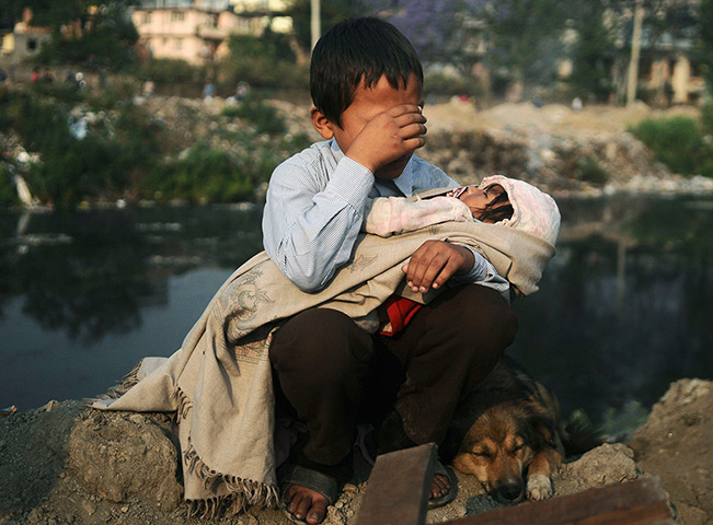 24 hours in pictures: A boy cries as he holds his sister in his lap, Nepal