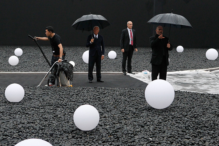 24 hours in pictures: Giorgio Armani holds an umbrella as he inspects the venue, China