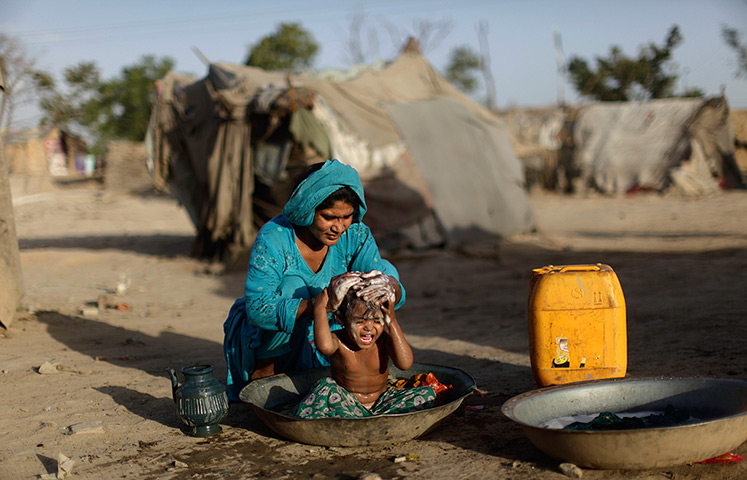 24 hours in pictures: A Pakistani woman bathes her daughter in a tub in a slum