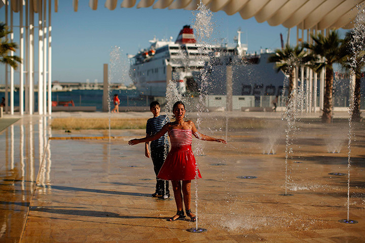24 hours: Malaga, Spain: A girl and a boy cool off in a fountain