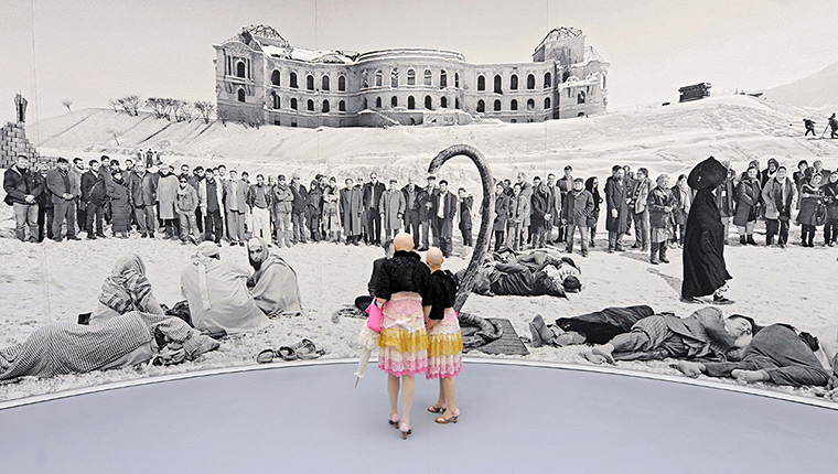 dOCUMENTA (13): Performers Eva and Adele walk in front of Goshka Macuga's work