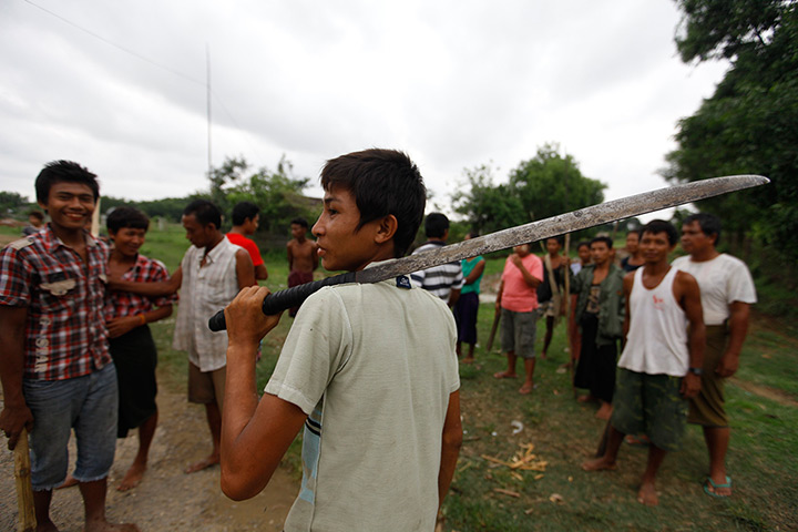 Burma violence: A Buddhist man holds a machete as he guards homes in Sittwe