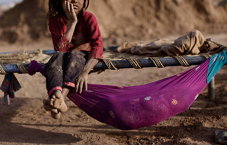 24 hours in pictures: Girl in a brick factory rests on a bed next to her sister, Pakistannagda 