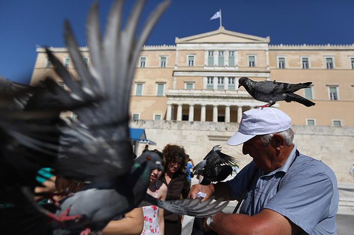 24 hours in pictures: A man is surrounded by pigeons outside the Athens Parliament building