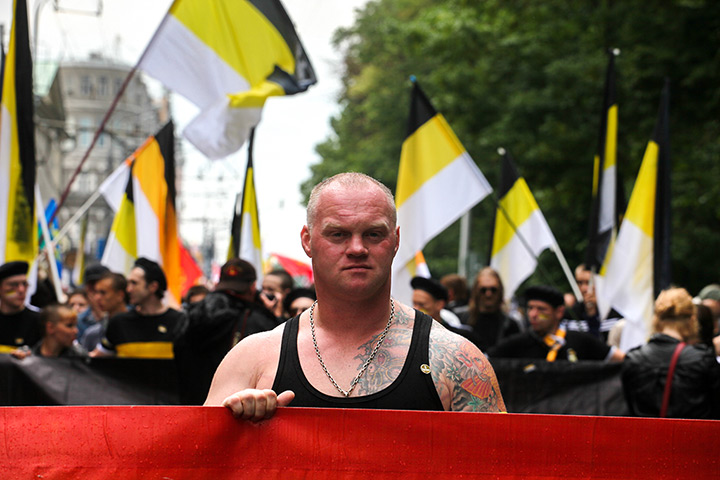Moscow protests: A man holds onto a banner in front of protesters holding nationalist flags