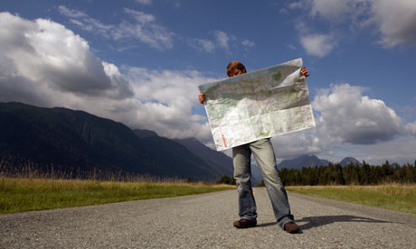 Man standing on rural road reading road map