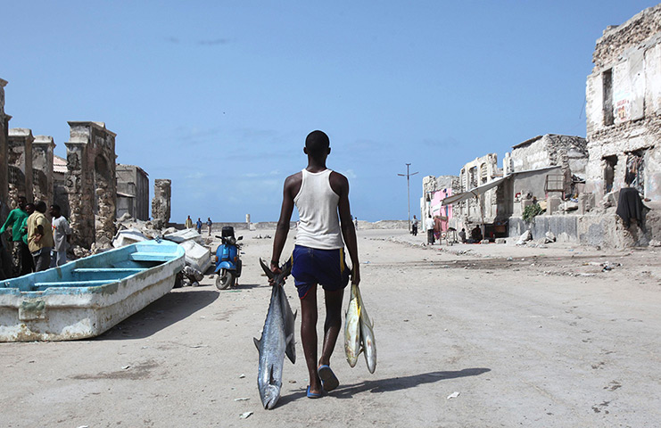 24 hours: Mogadishu, Somalia: A man carries fish from the shores of the Indian ocean