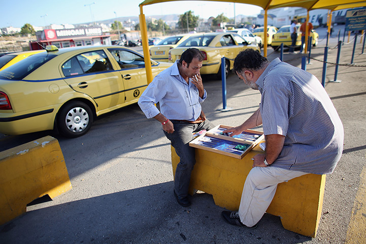 Greece: 13-14 June: Taxi drivers play a game of backgammon as they wait at a rank in Piraeus