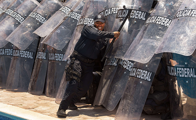 24 hours in pictures: A Mexican Federal Police instructor pushes on the shields of a riot squad 