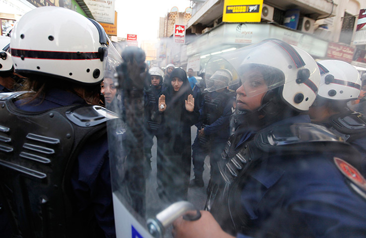 24 hours in pictures: An anti-government protester gestures as she is detained by riot police