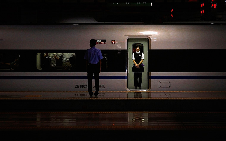 24 hours in pictures: An usher waits in the doorway of a train, Beijing