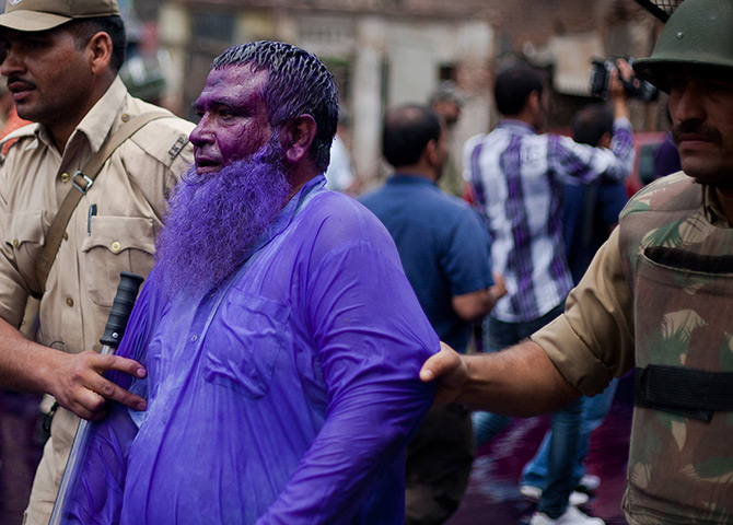 24 hours in pictures: Police detain a man dyed with purple coloured water from a water canon