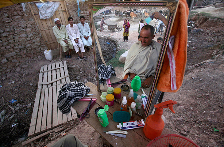 24 hours in pictures: A Pakistani street barber gives a haircut to a customer