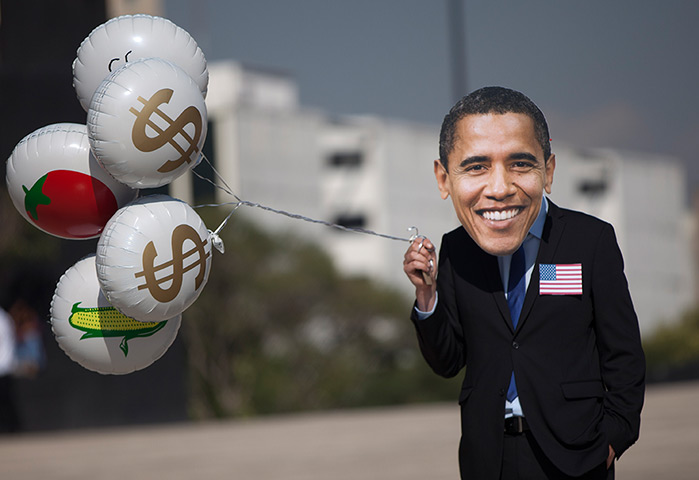 24 hours in pictures: An Oxfam activist wearing a mask depicting Barack Obama holds balloons