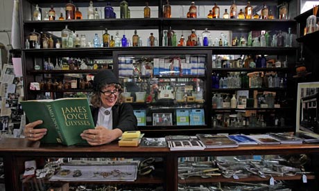 Wendy Conroy in period costume with a copy of Ulysses in Sweny's Pharmacy in Dublin