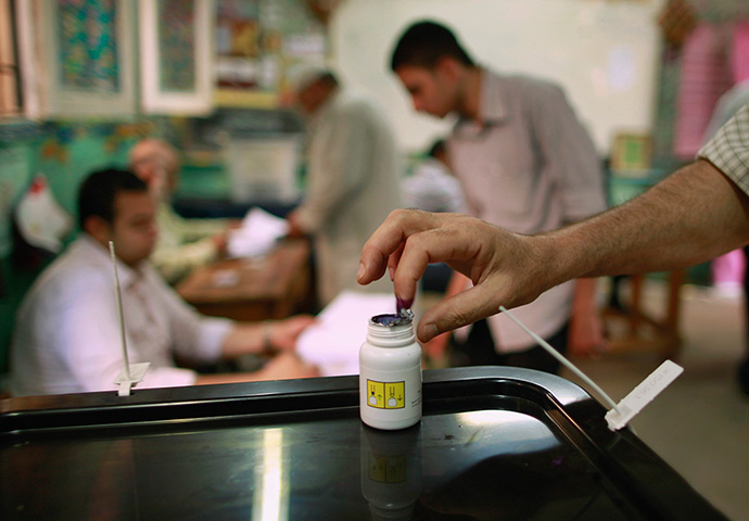 Egypt elections day 2: A voter dips his finger in a bottle of ink after casting his vote