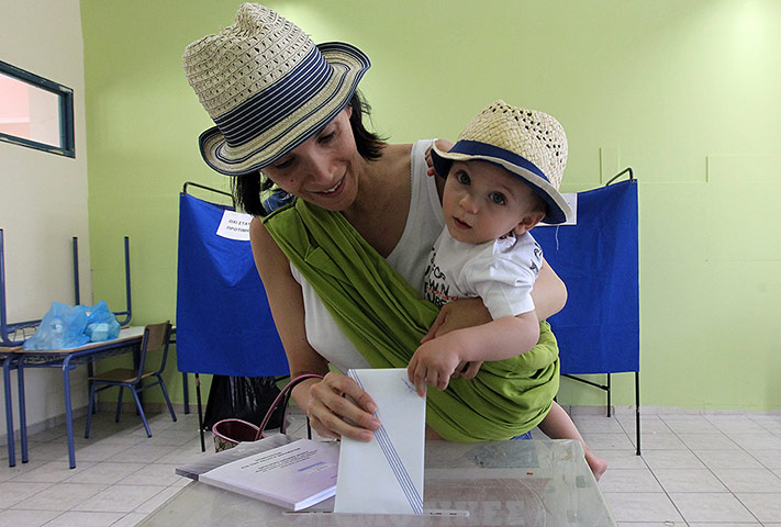 Greek elections: A woman holds her child as she casts her ballot