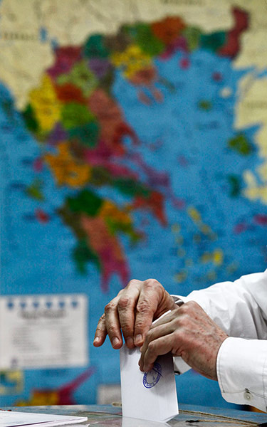 Greek elections: A voter casts his ballot in front of a map of Greece
