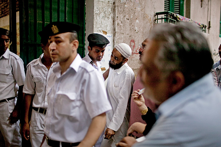 Egypt elections day 2: Egyptian men pass police to enter a polling station in Cairo