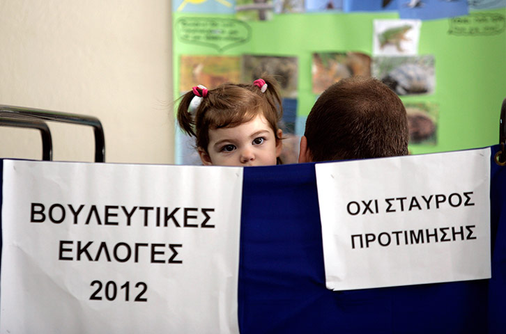 Greek vote: A man holds his daughter while he casts his vote at a polling station