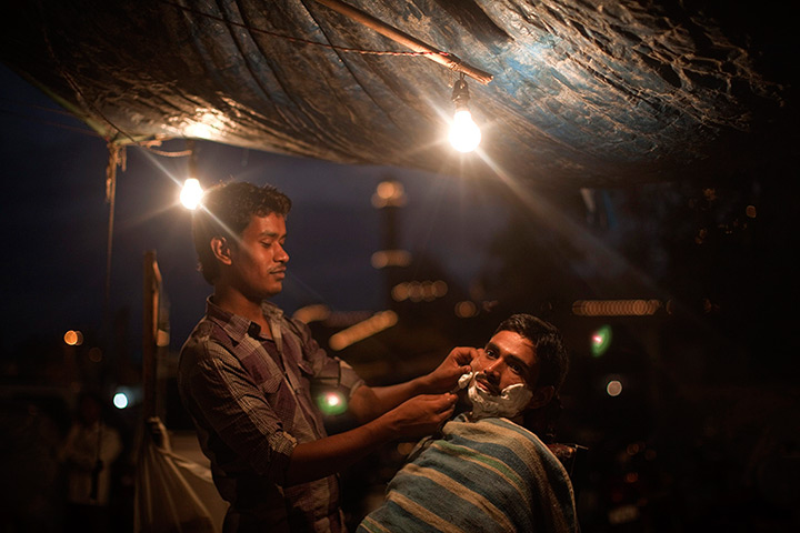 24 hours in pictures: A man gets a shave from a roadside barber at night