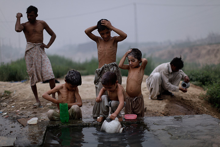 24 hours in pictures: Pakistani children shower at a water reservoir